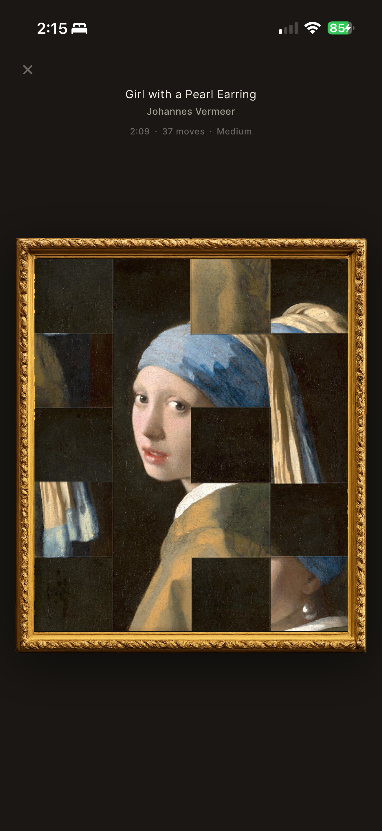 Cadrelle app on iPhone: restoring Girl with a Pearl Earring as a puzzle, pieces falling into place within a gilt frame.